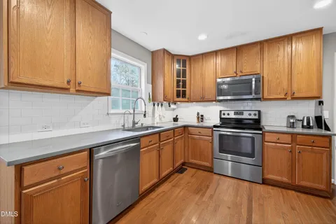 a kitchen with stainless steel appliances granite countertop wooden cabinets a sink and a stove