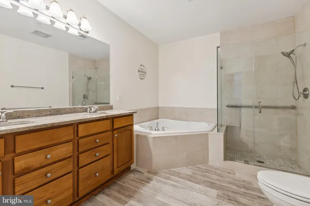 a spacious bathroom with double sink a toilet a shower and a mirror