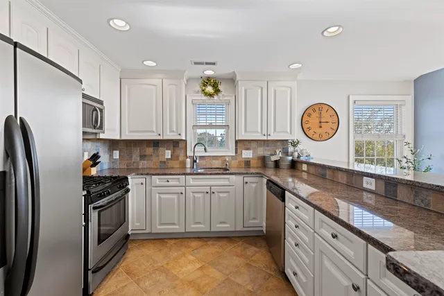 a kitchen with stainless steel appliances granite countertop a stove a sink and a refrigerator