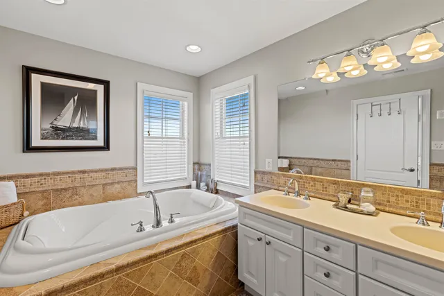 a bathroom with a tub a double vanity sink and a mirror