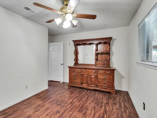 an empty room with wooden floor cabinet and a ceiling fan