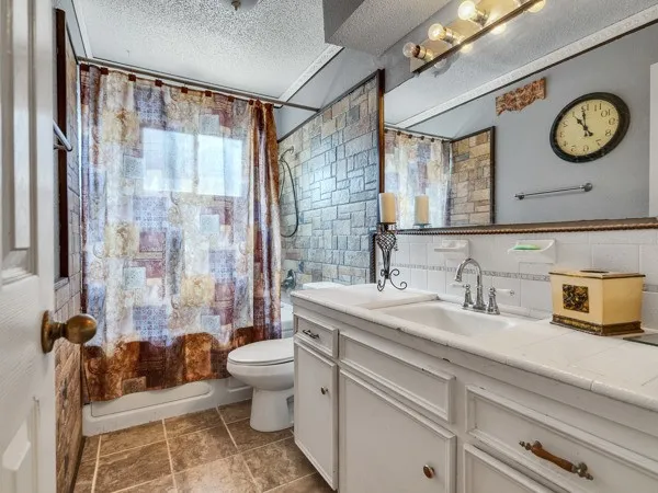 a bathroom with a granite countertop sink mirror vanity and toilet