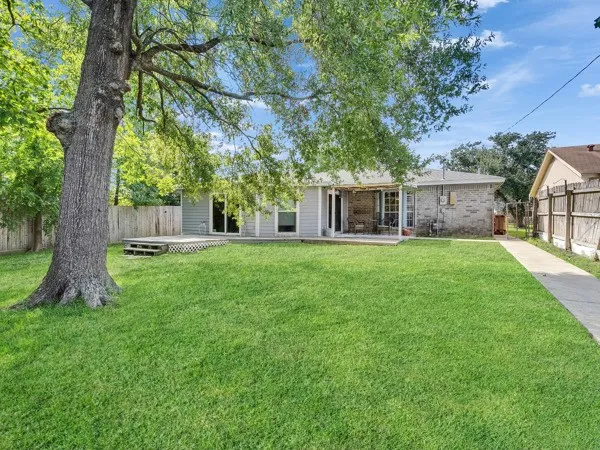 a view of a house with a big yard and large tree