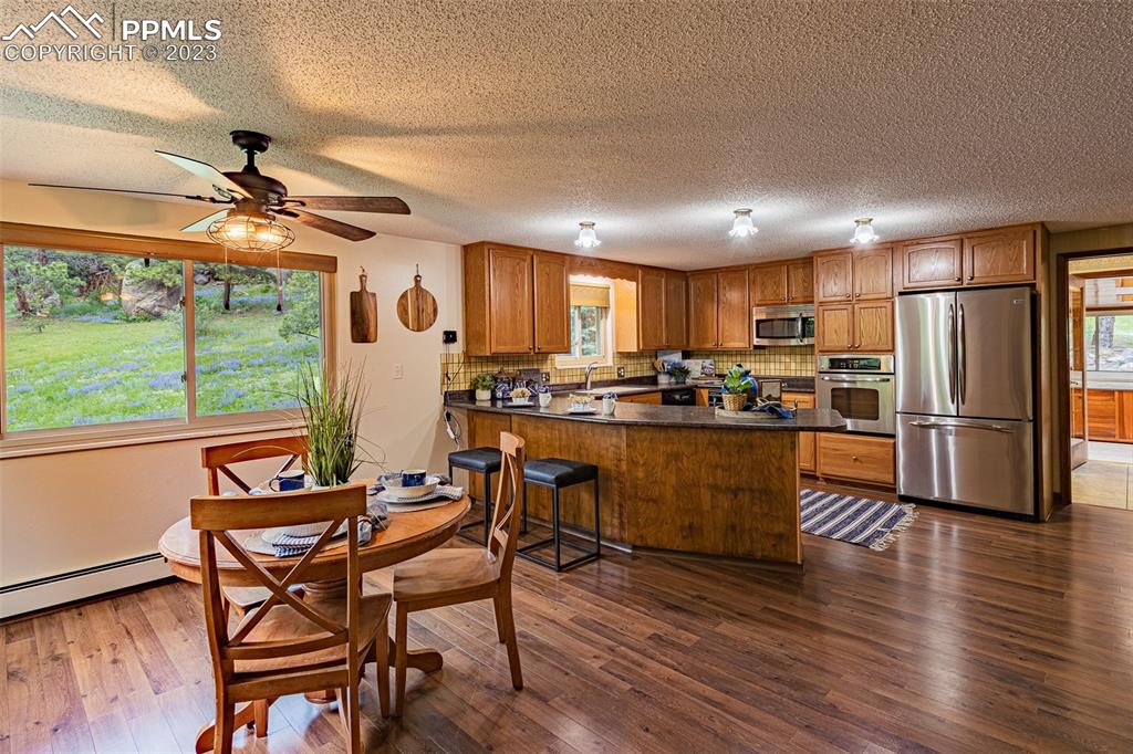 98 Button Rock Road Lyons, CO 80540 - Photo 4 of 49 a kitchen with stainless steel appliances granite countertop a refrigerator a stove a sink a dining table and chairs with wooden floor