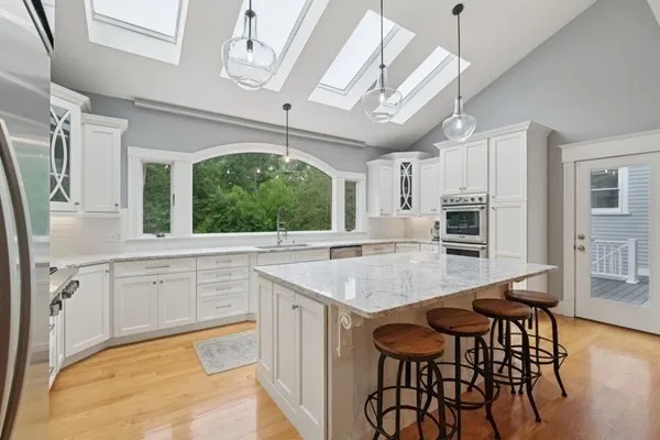 a kitchen with stainless steel appliances granite countertop a table chairs sink and cabinets