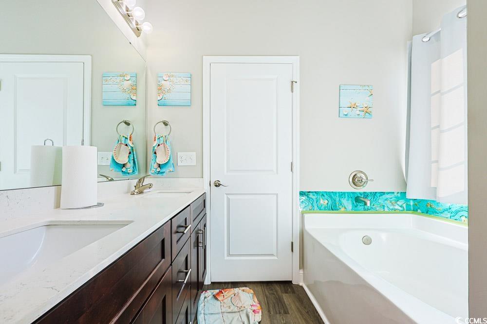 724 Hobonny Loop Longs, SC 29568 - Photo 15 of 40 Bathroom featuring a garden tub, double vanity, and dark wood-type flooring