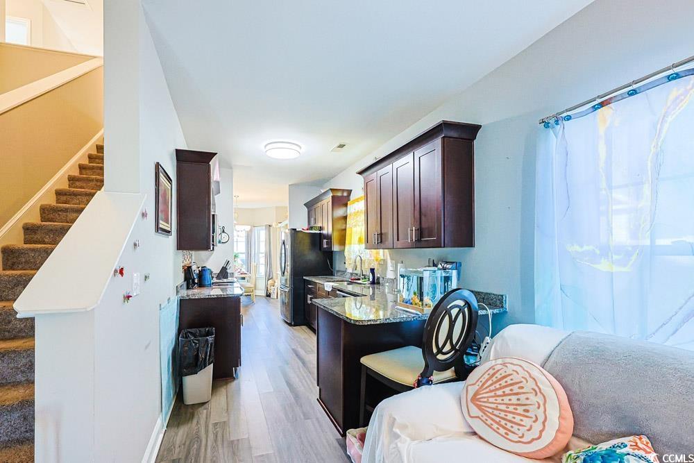 724 Hobonny Loop Longs, SC 29568 - Photo 5 of 40 Kitchen featuring dark brown cabinets, light stone countertops, a peninsula, light wood finished floors, and a breakfast bar
