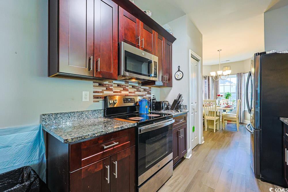 724 Hobonny Loop Longs, SC 29568 - Photo 6 of 40 Kitchen featuring appliances with stainless steel finishes, reddish brown cabinets, decorative backsplash, dark stone counters, and pendant lighting