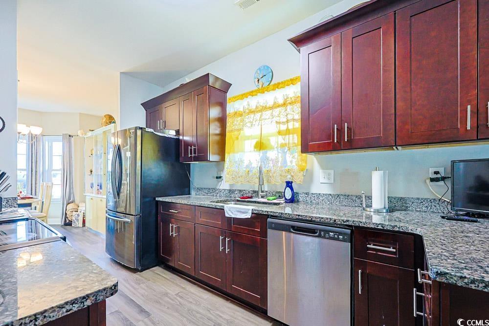 724 Hobonny Loop Longs, SC 29568 - Photo 7 of 40 Kitchen with appliances with stainless steel finishes, dark brown cabinets, and light stone counters
