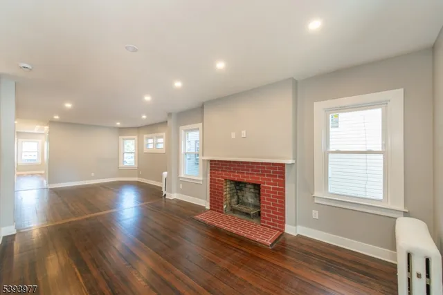 an empty room with wooden floor fireplace and windows