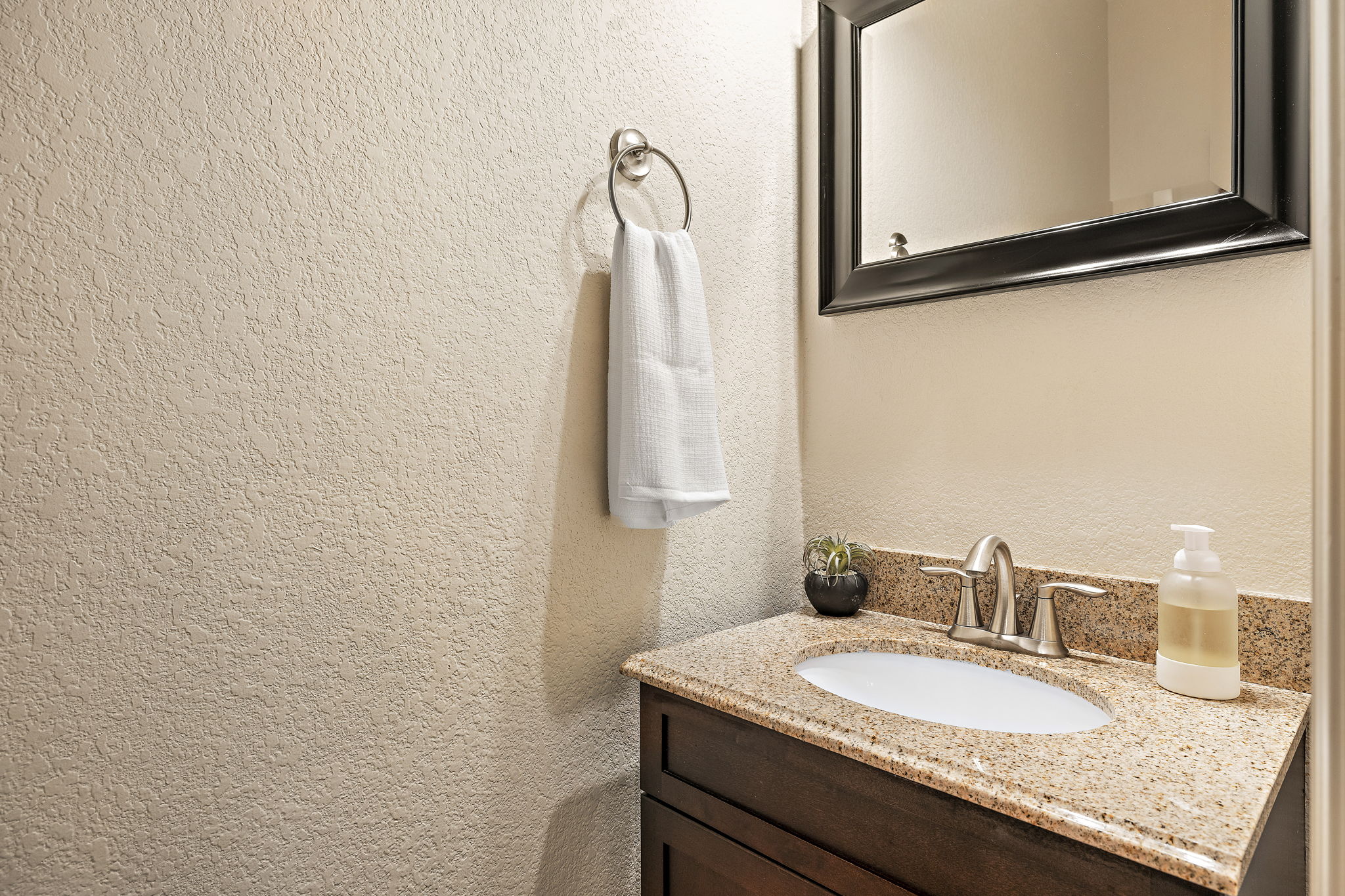 6708 Menchaca Road, Unit 10 Austin, TX 78745 - Photo 23 of 28 Vanity featuring a light-toned granite countertop with an undermount sink, brushed nickel faucet, and dark wood-finish cabinetry