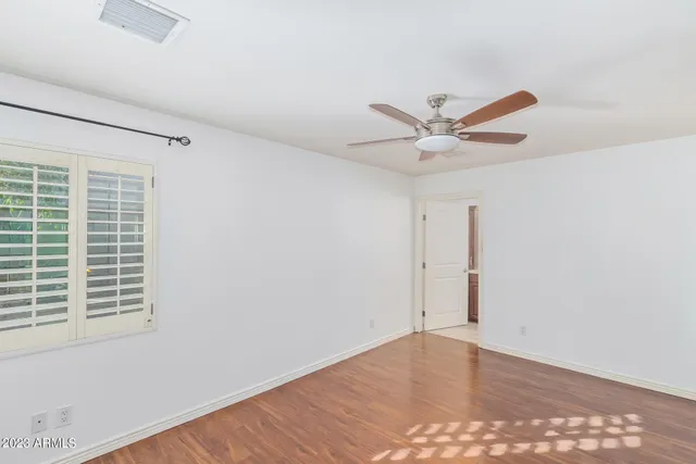 an empty room with wooden floor and ceiling fan