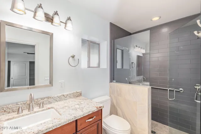 a bathroom with a granite countertop sink mirror vanity and toilet