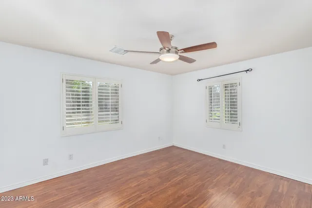 a view of an empty room with a window and wooden floor