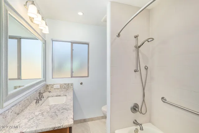 a bathroom with a granite countertop sink a mirror and shower