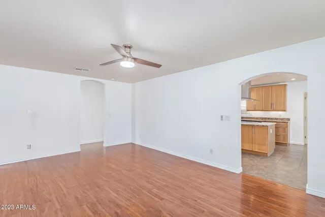 a view of empty room with wooden floor and ceiling fan