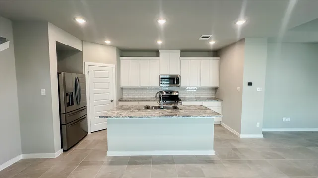 a large kitchen with stainless steel appliances granite countertop a sink stove and refrigerator