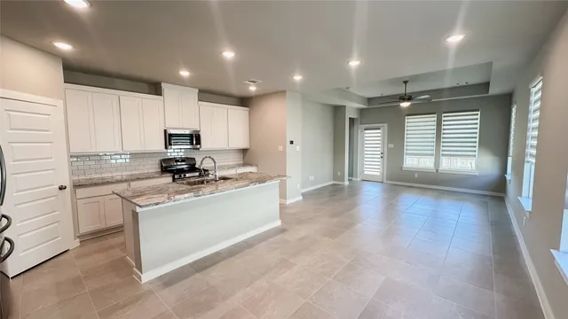 a kitchen with stainless steel appliances granite countertop a stove a sink and a refrigerator with wooden floor