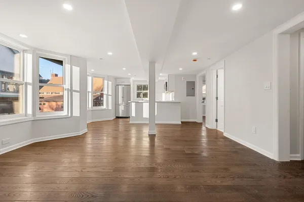 a view of an empty room with a window and wooden floor