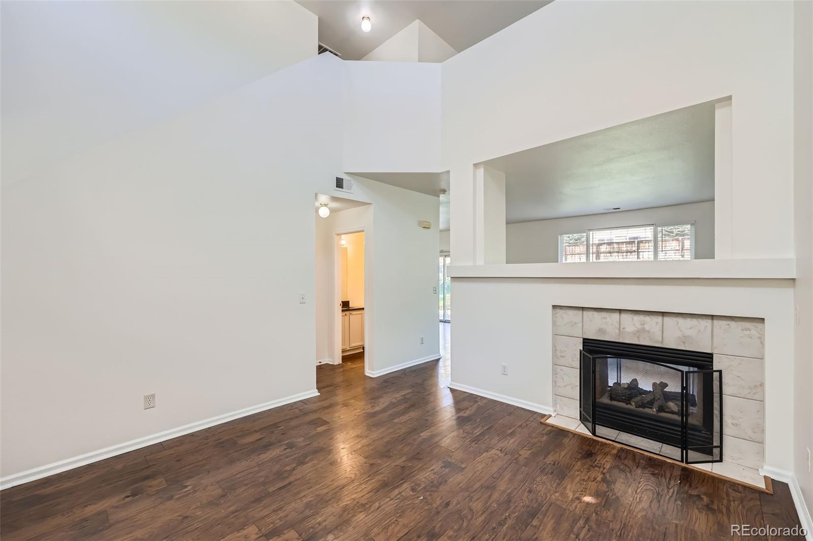 10562 Tracewood Circle Highlands Ranch, CO 80130 - Photo 5 of 28 a view of an empty room with wooden floor fireplace and a window