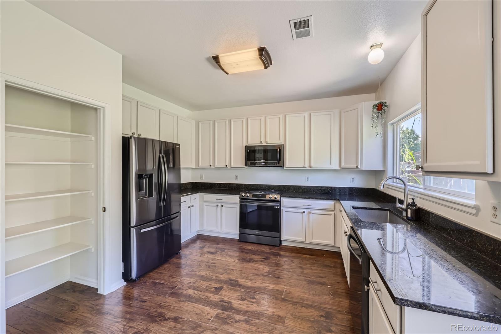 10562 Tracewood Circle Highlands Ranch, CO 80130 - Photo 7 of 28 a kitchen with granite countertop a refrigerator stove and sink
