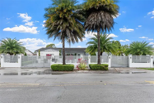 front view of house with a yard and palm trees