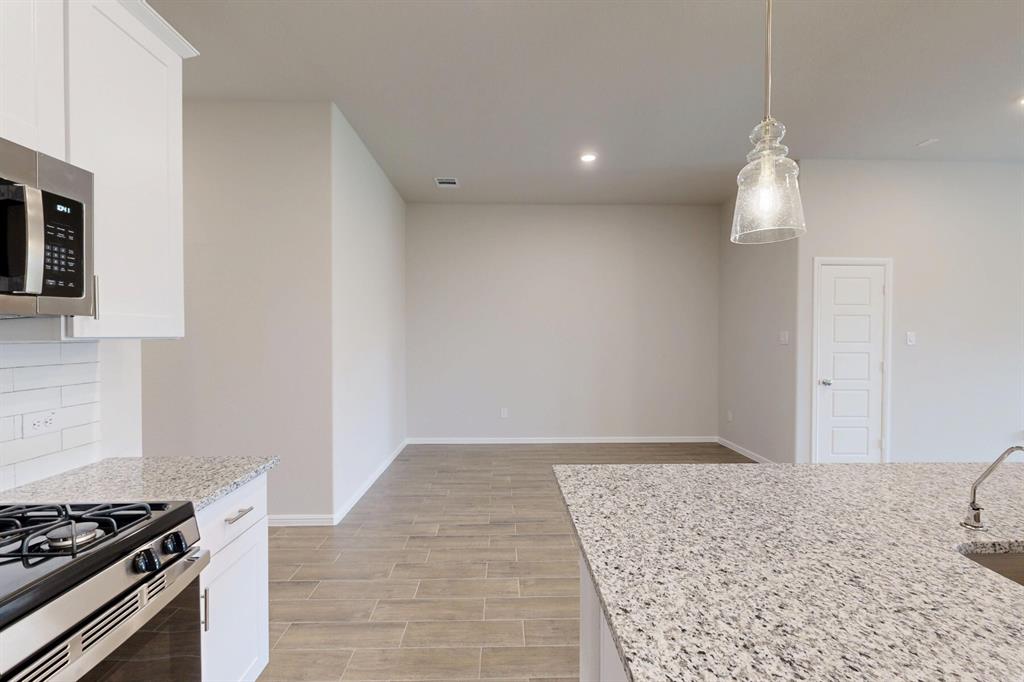 408 Wydown Drive Princeton, TX 75407 - Photo 17 of 40 a kitchen with a stove and a wooden floor