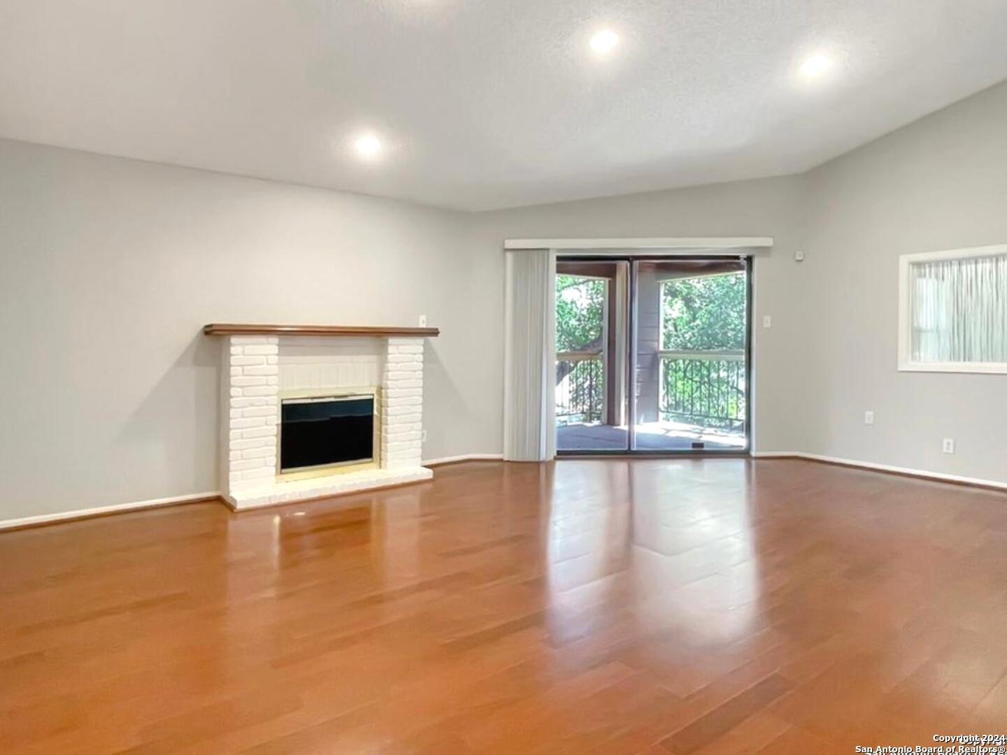 11520 Huebner Road, Unit 107 San Antonio, TX 78230 - Photo 6 of 22 an empty room with wooden floor and fireplace