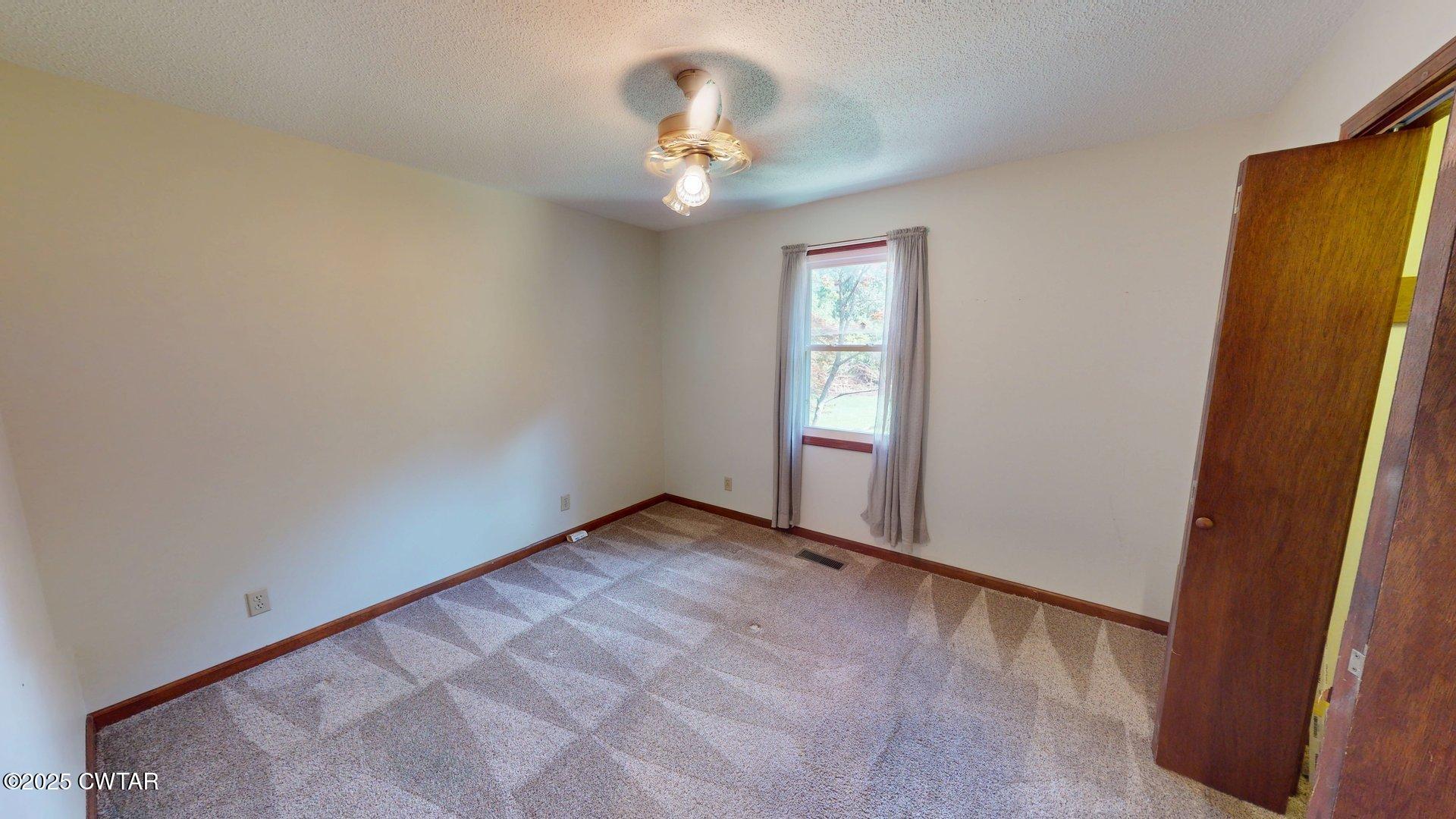 1921 Forrester Road Newbern, TN 38059 - Photo 14 of 18 an empty room with windows and chandelier fan