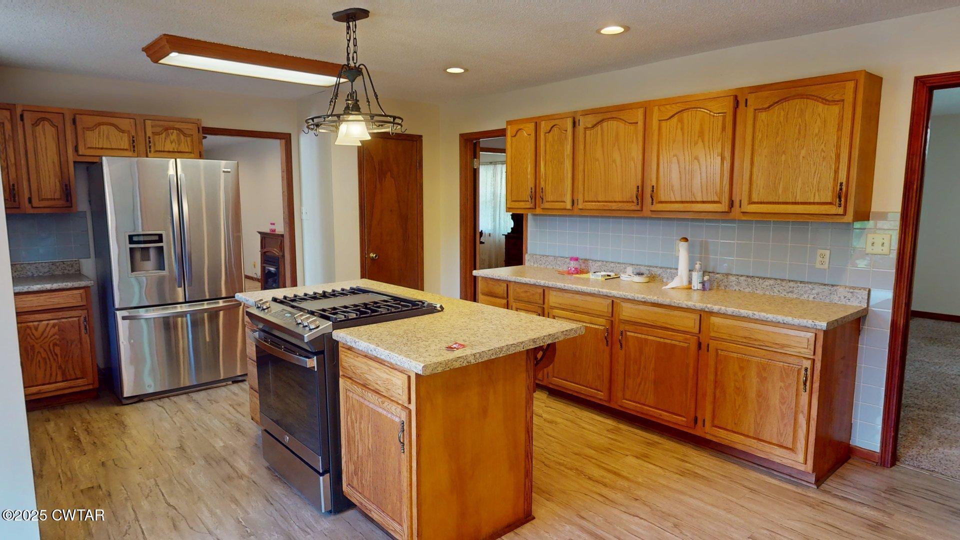 1921 Forrester Road Newbern, TN 38059 - Photo 5 of 18 a kitchen with stainless steel appliances granite countertop a refrigerator a sink dishwasher a stove and white countertops with wooden floor