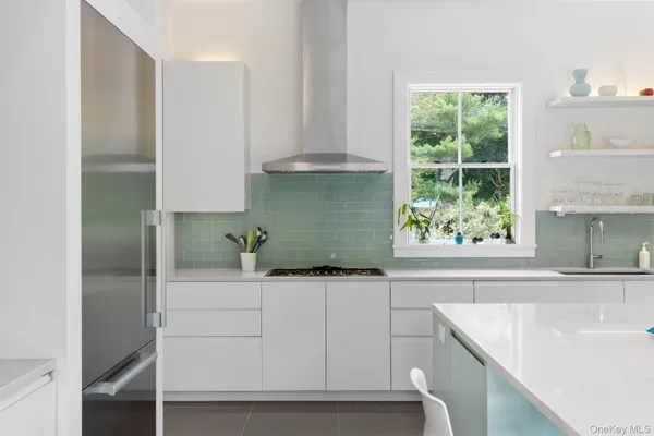 a kitchen with white cabinets and a window