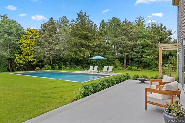 a view of a swimming pool and lounge chairs in back of the house