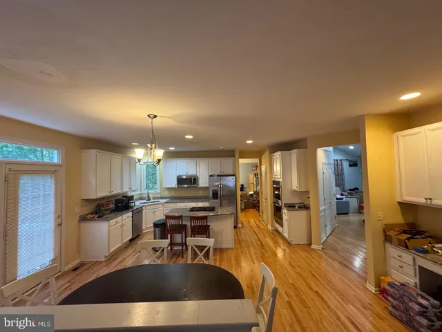 a kitchen with stainless steel appliances a dining table chairs and stove
