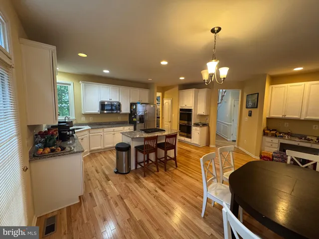 a kitchen with stainless steel appliances a dining table chairs stove microwave and cabinets