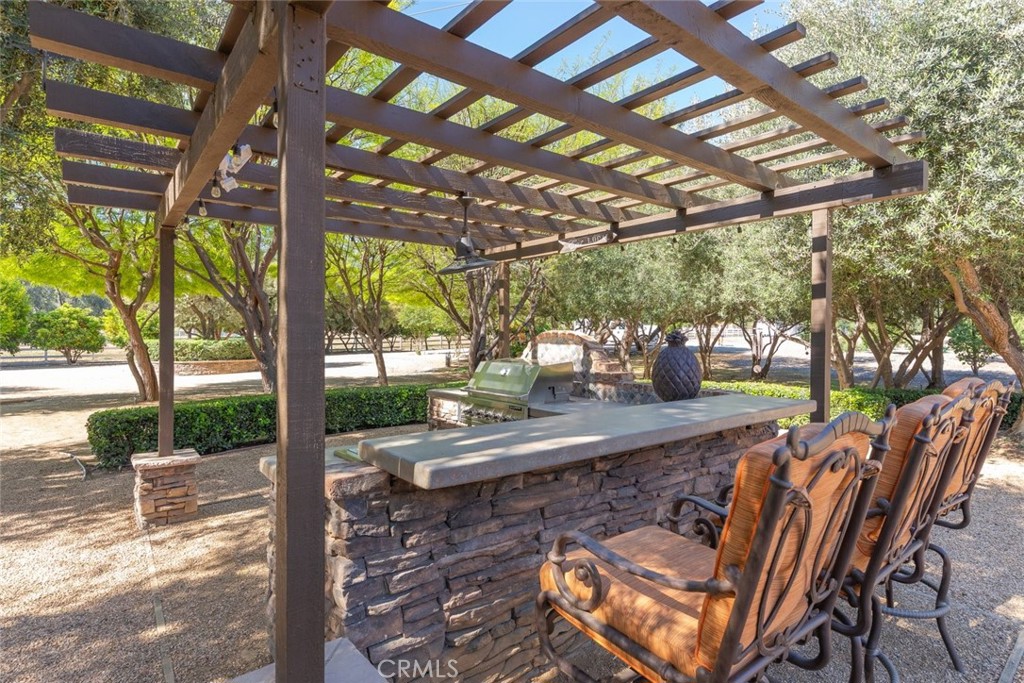 23965 Lawson Road Corona, CA 92883 - Photo 47 of 74 a view of a patio with table and chairs under an umbrella with a large tree