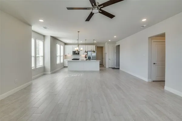 a living room with stainless steel appliances furniture cabinets and a wooden floor
