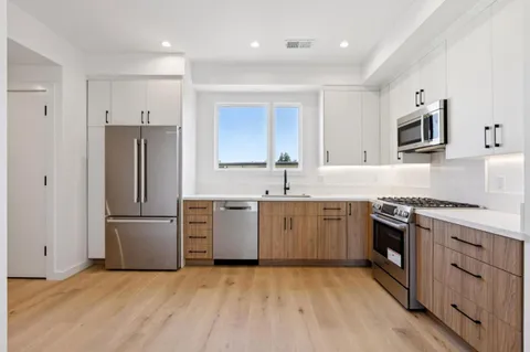 a kitchen with granite countertop a refrigerator stove top oven and sink