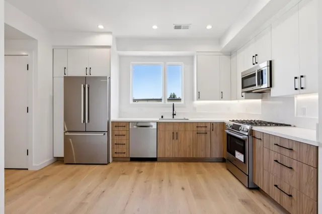 a kitchen with granite countertop a refrigerator stove top oven and sink