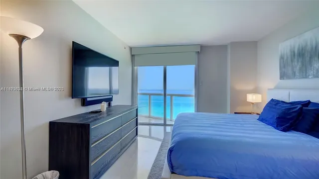 a bedroom with a large bed and a flat tv screen on dresser