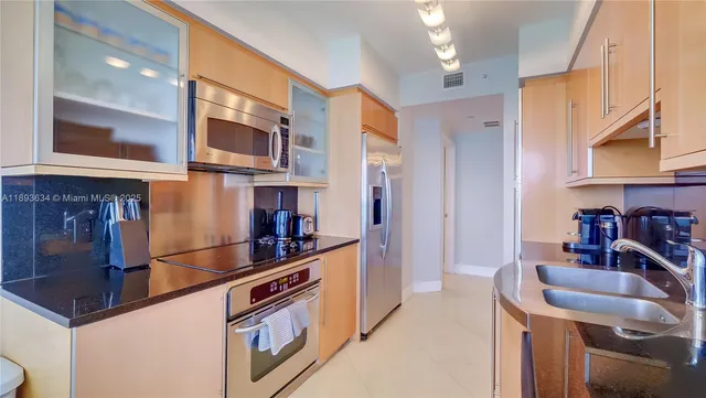 a kitchen with stainless steel appliances granite countertop a sink and a refrigerator