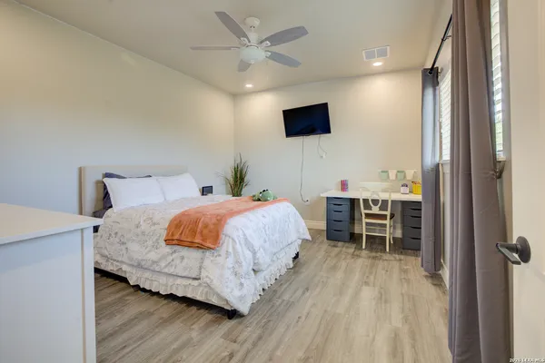 a spacious bedroom with a bed and a flat screen tv
