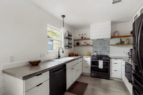 a kitchen with stainless steel appliances granite countertop a sink a stove and a refrigerator