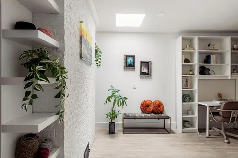 a hallway with painting on the wall and a potted plant