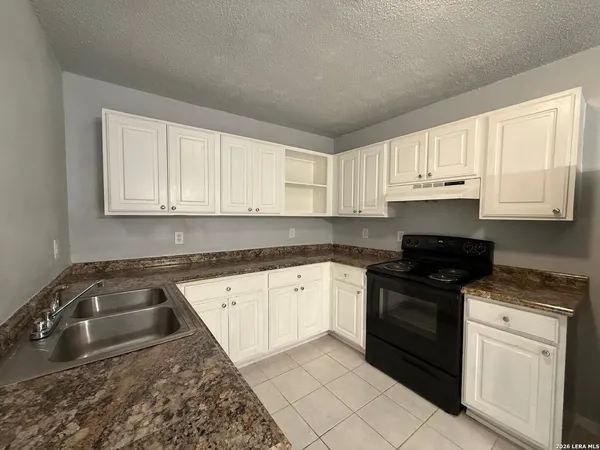 a kitchen with granite countertop white cabinets sink and stainless steel appliances
