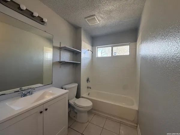 a bathroom with a granite countertop sink a toilet and shower