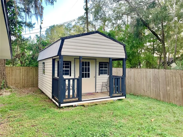 a view of a house with a yard plants and large tree