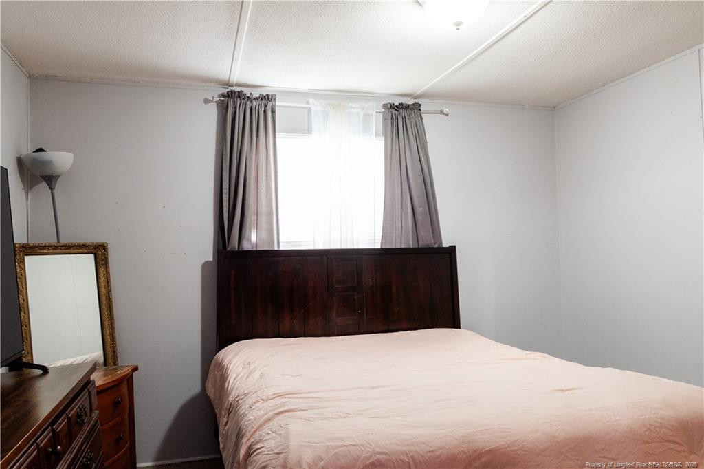231 Knight Lane Autryville, NC 28318 - Photo 21 of 27 a bedroom with a bed and a flat tv screen on the dresser