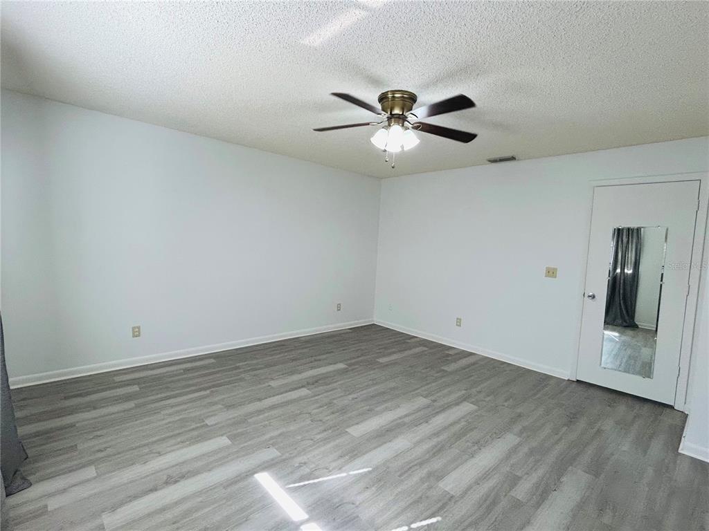 8530 Southwest 90th Street, Unit B Ocala, FL 34481 - Photo 5 of 45 a view of an empty room with wooden floor and a ceiling fan