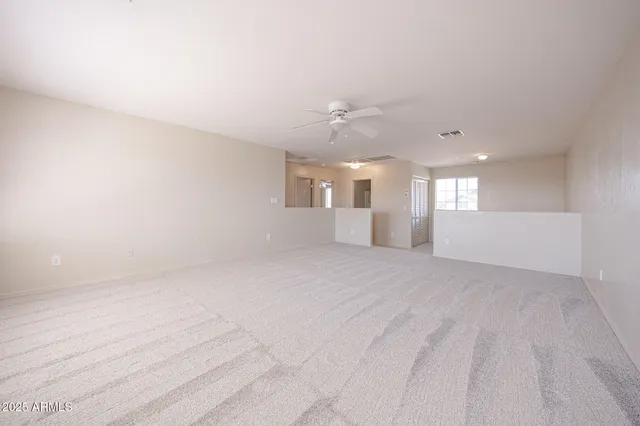 a view of a big room with windows and chandelier fan