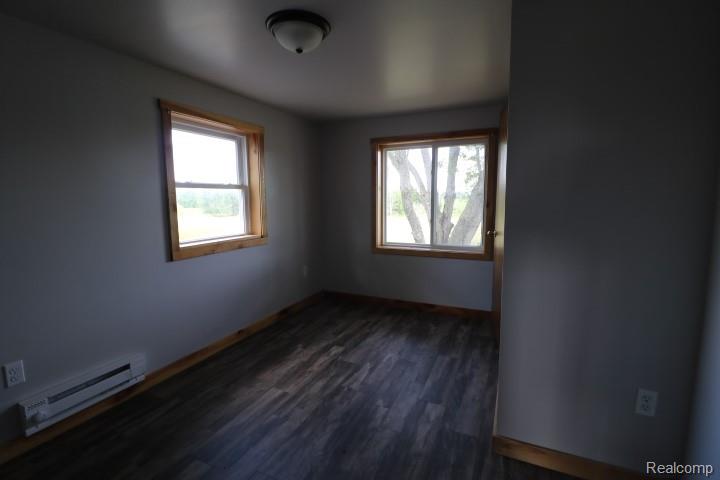 6577 East Deckerville Road Deford, MI 48729 - Photo 15 of 16 Neutral gray walls with wood-finish flooring, two windows with wood trim, and a flush mount ceiling light